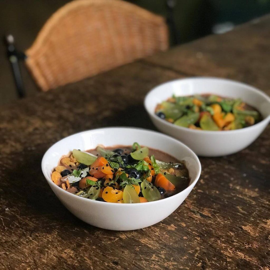 two white bowls with chocolate pudding and freshly cut fruit